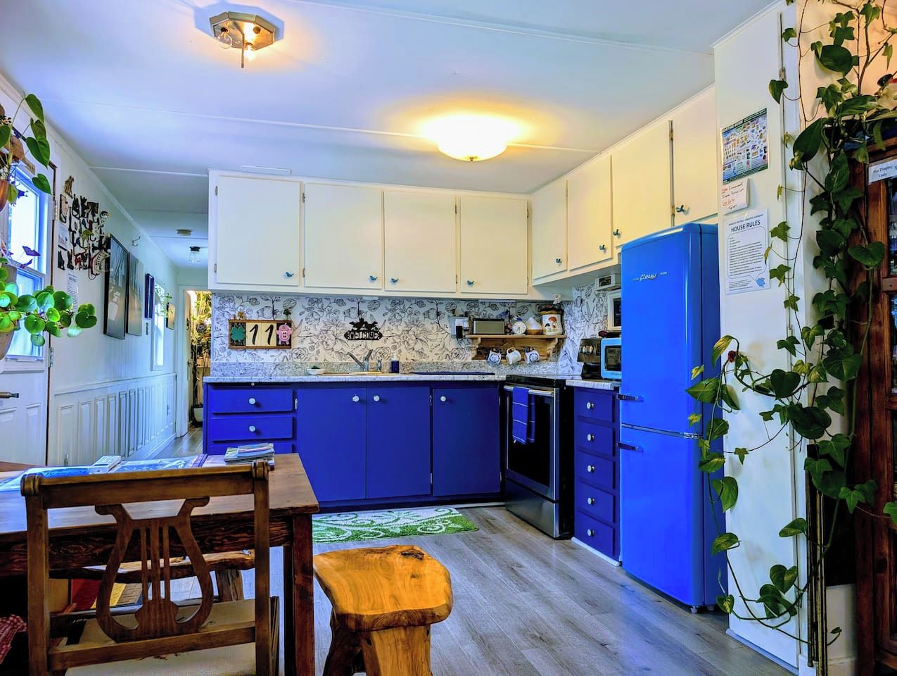 Une cuisine avec des meubles de rangement bleus, une table à manger en bois et un réfrigérateur.