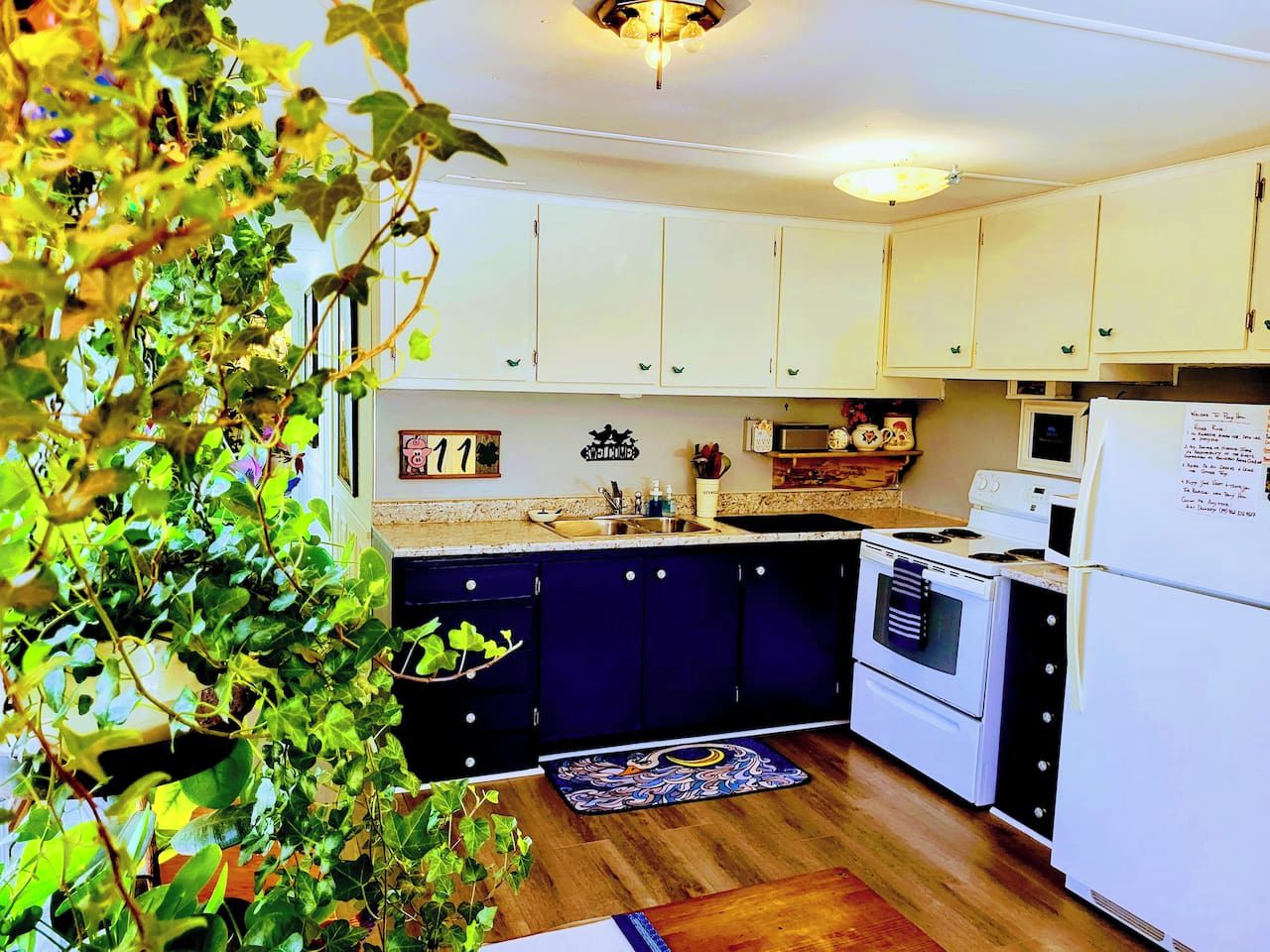 Una cocina con armarios blancos, estufa, microondas y refrigerador.