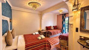 A hotel room with two beds, a sitting area, a mirror, and a chandelier. - auberge tissadrine (Drâa-Tafilalet)