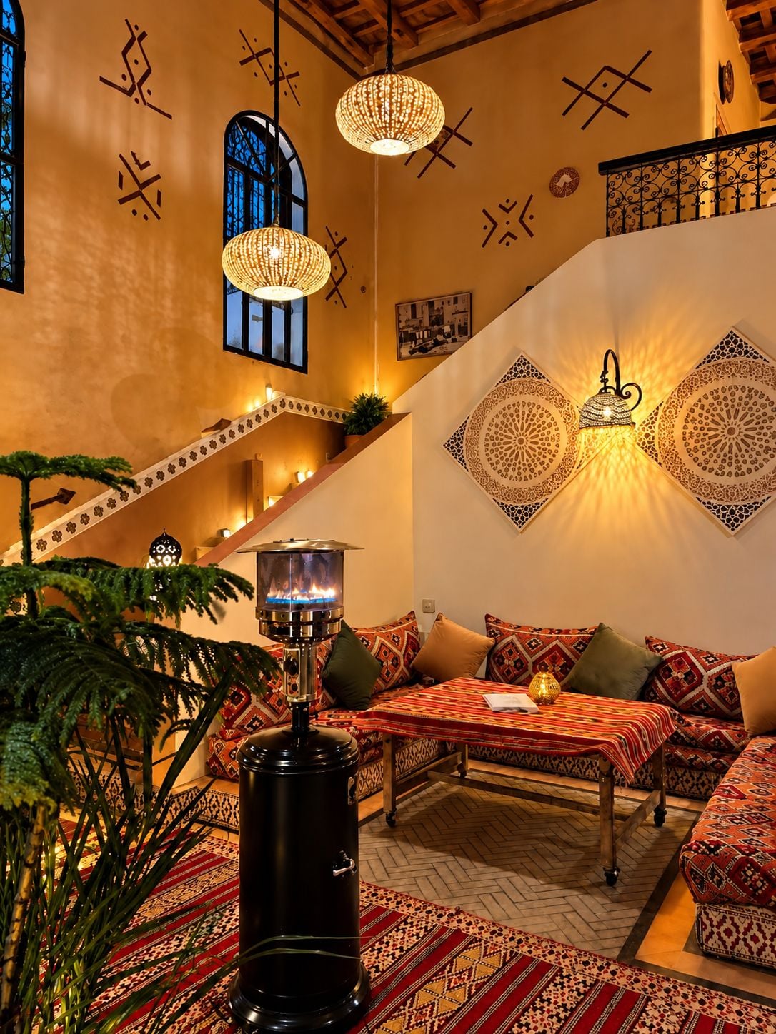 A cozy interior with a sofa set, patterned cushions, a decorative wall, and a hanging lamp.