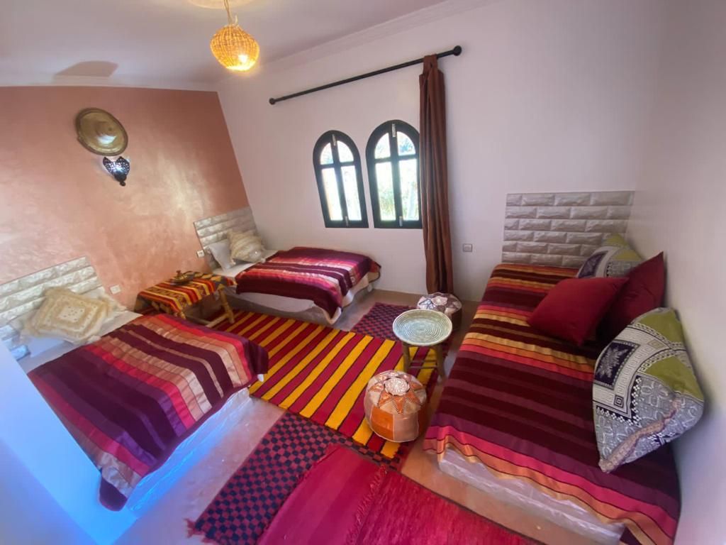Quarto com duas camas, um sofá e uma janela com cortinas.