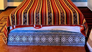 A hotel room with a large bed, a decorative ceiling light, and a blue textured wall. - auberge tissadrine (Drâa-Tafilalet)