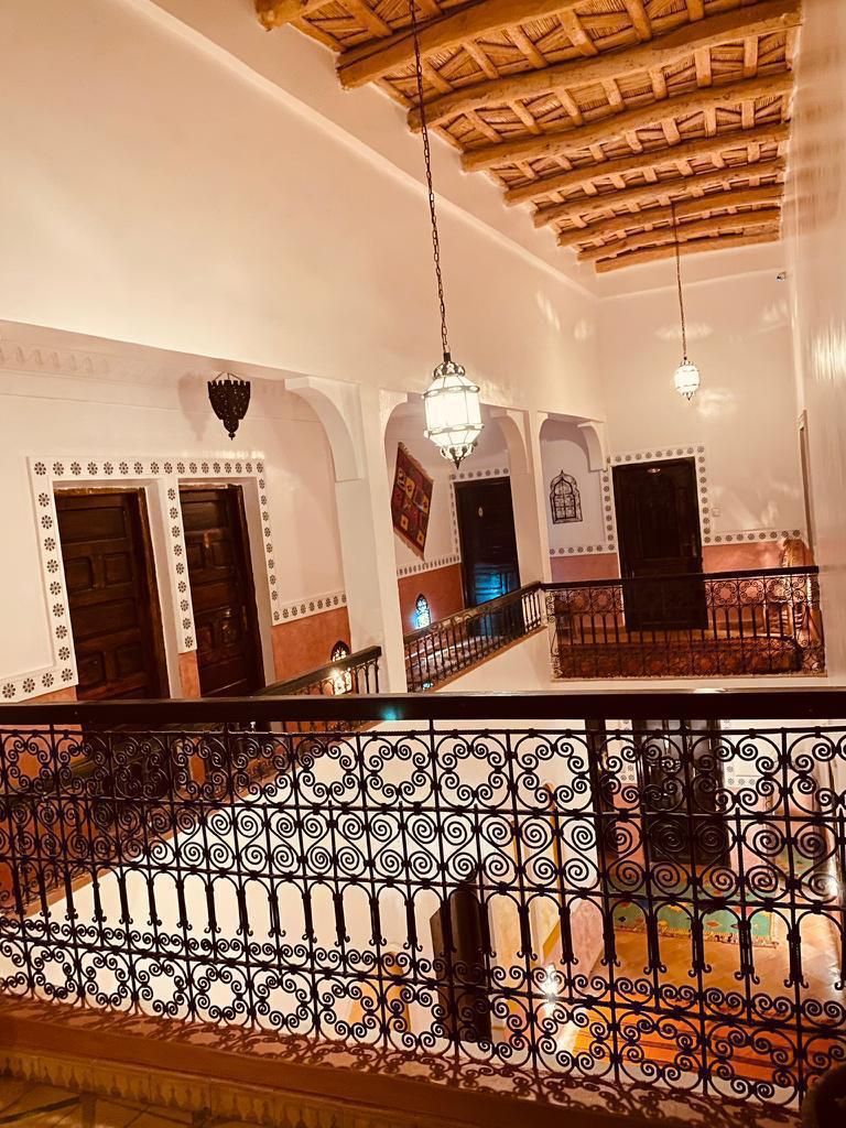 An interior with a wooden ceiling, arched doorways, and a balcony with ornate metal railings.