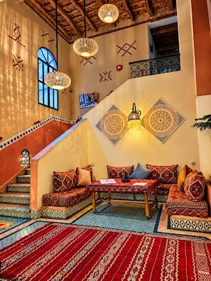 A traditional interior with a staircase, patterned cushions, and decorative wall art. - auberge tissadrine (Ait Sedrate Jbel El Soufla)