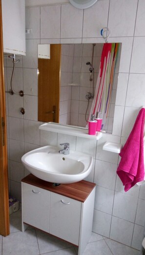Een badkamer met een wit wastafel, een houten kastje en een spiegel erboven.