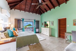 Ein Schlafzimmer mit Bett, Schminktisch, Schreibtisch und Blick auf den Ozean.