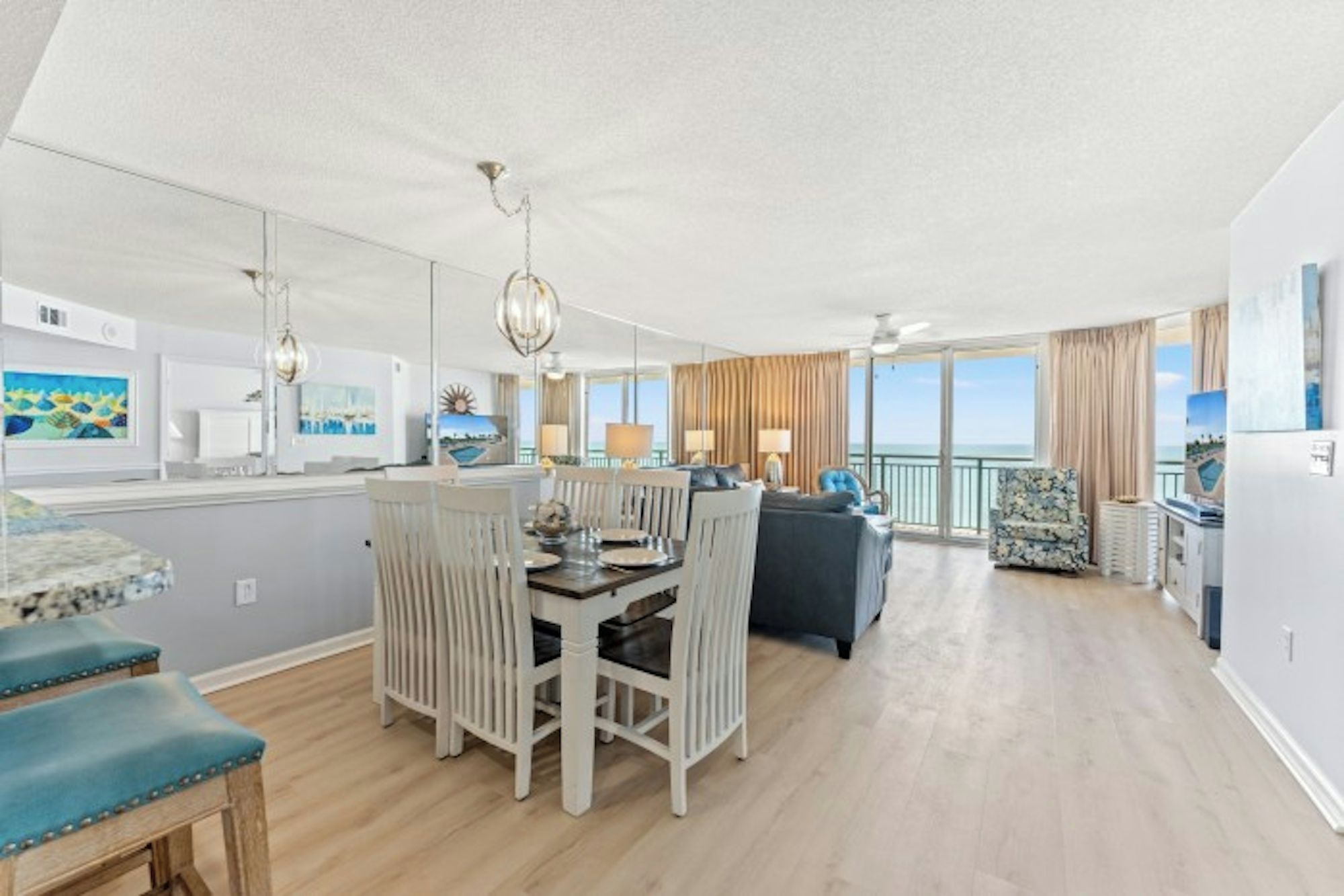 A spacious living area with a dining table, seating, and a view of the sea.