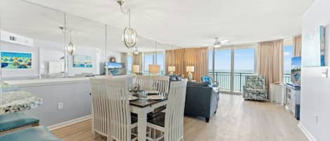 Een ruime woonkamer met een eettafel, zitplaatsen en uitzicht op zee.