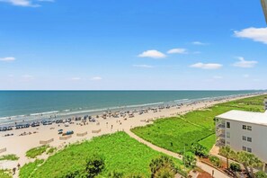 A beach with a clear sky, a sandy shore, and a building with a flat roof. - Oceanfront 3BR- Windy Hill Dunes 705- Lazy River (North Myrtle Beach)