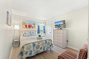 A bedroom with a bed, a dresser, a television, and artwork on the walls. - Oceanfront 3BR- Windy Hill Dunes 705- Lazy River (North Myrtle Beach)