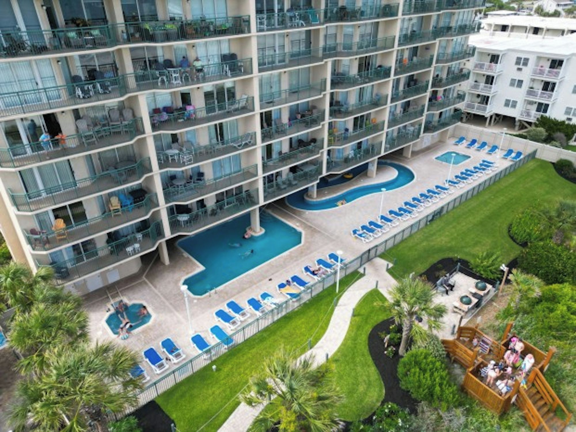 A multi-story hotel with a rooftop pool and outdoor seating areas.