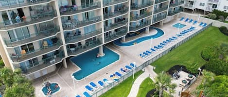 A multi-story hotel with a rooftop pool and outdoor seating areas.