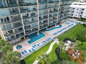 A multi-story hotel with a rooftop pool and outdoor seating areas. - Oceanfront 3BR- Windy Hill Dunes 705- Lazy River (North Myrtle Beach)