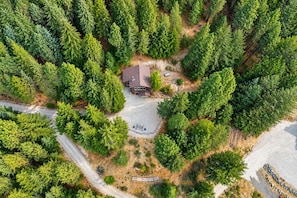 An aerial view of a residential property surrounded by dense forest, featuring a central house with a paved driveway and a small garden area. - New Listing|Forest|Sleeps 6 | BBQ Grill | Dogs OK (Leavenworth)