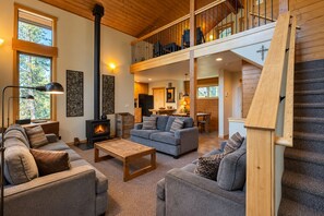 Ein großzügiger Wohnbereich mit Kamin, Sofas und einer Treppe zu einer oberen Ebene.