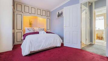 A bedroom with a bed, a door, and a view of a balcony.