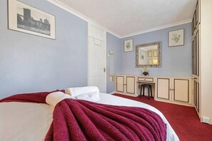 Une chambre à coucher avec un lit, une commode, un miroir et une porte.
