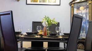 Una mesa de comedor dispuesta con platos, vasos y un florero con planta.