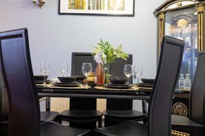Une table à manger dressée avec des assiettes, des verres et un vase contenant une plante.