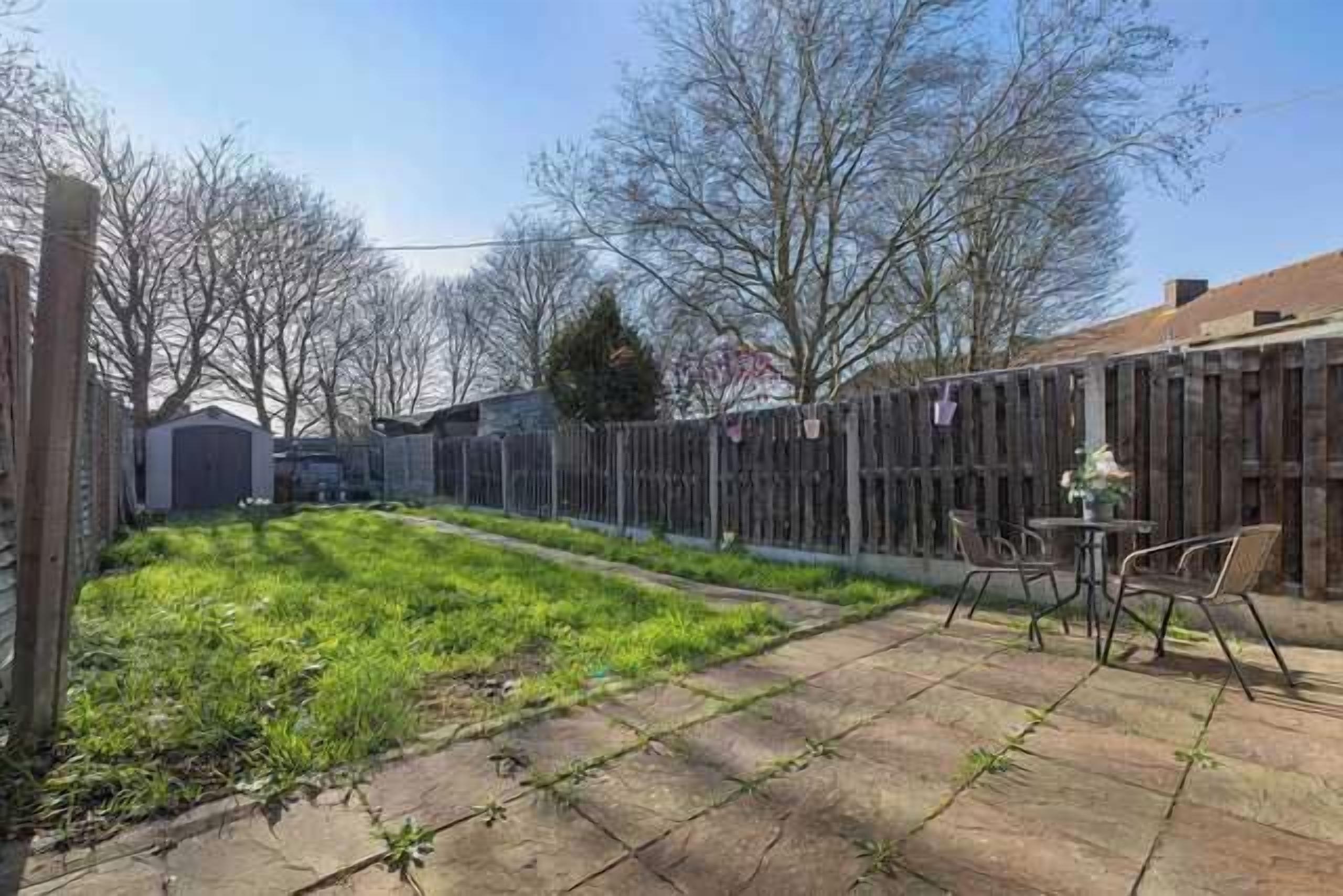A backyard with a patio, a wooden fence, and a small table with chairs.
