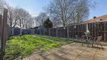 A backyard with a patio, a wooden fence, and a small table with chairs.