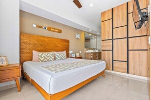 Ein modernes Schlafzimmer mit einem Holzkopfteil, einem großen Bett mit gemusterten Betttextilien, einem Nachttisch, einem Spiegel und einer Holzwand.