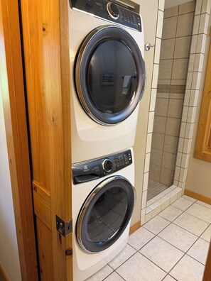A front view of a stacked washer and dryer unit with a wooden door frame. - The ‘Little House’ in Black Mountain (Black Mountain)