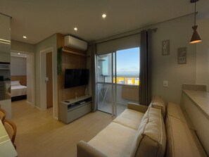 Una sala moderna con un sofá, un televisor de pantalla plana y un balcón con vistas.
