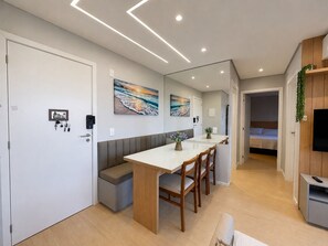 Un interior moderno con comedor, un banco, un pequeño rincón de asientos y un televisor.