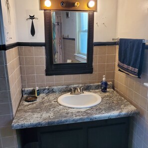 Un baño con lavamanos, espejo y perchero para toallas.