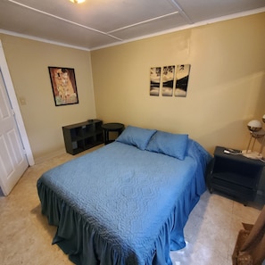 Un dormitorio con cama, mesita de noche, escritorio y decoración en la pared.