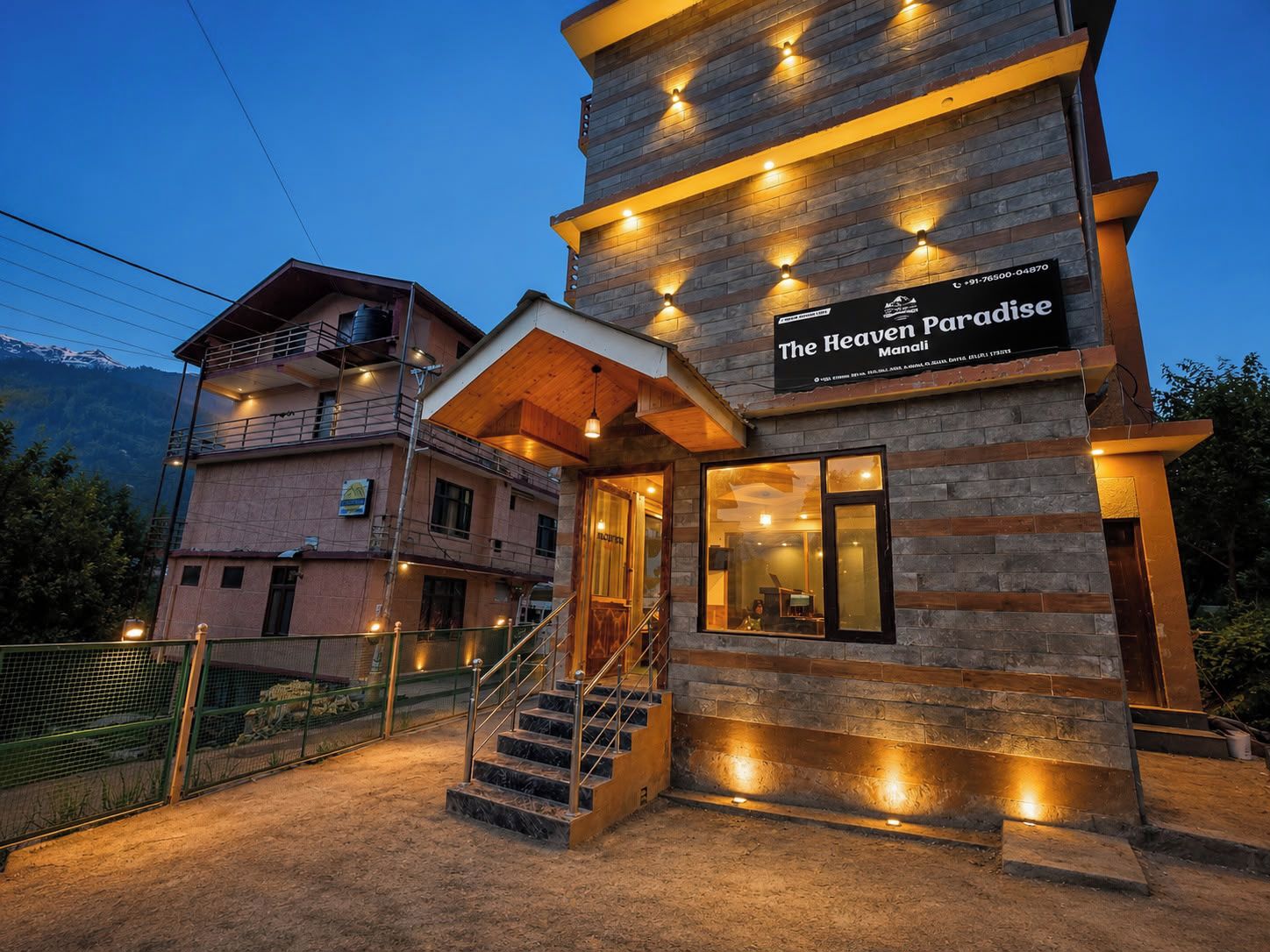 A hotel named 'The Heaven Paradise' with a stone facade, a staircase leading to the entrance, and a view of the mountains in the background.