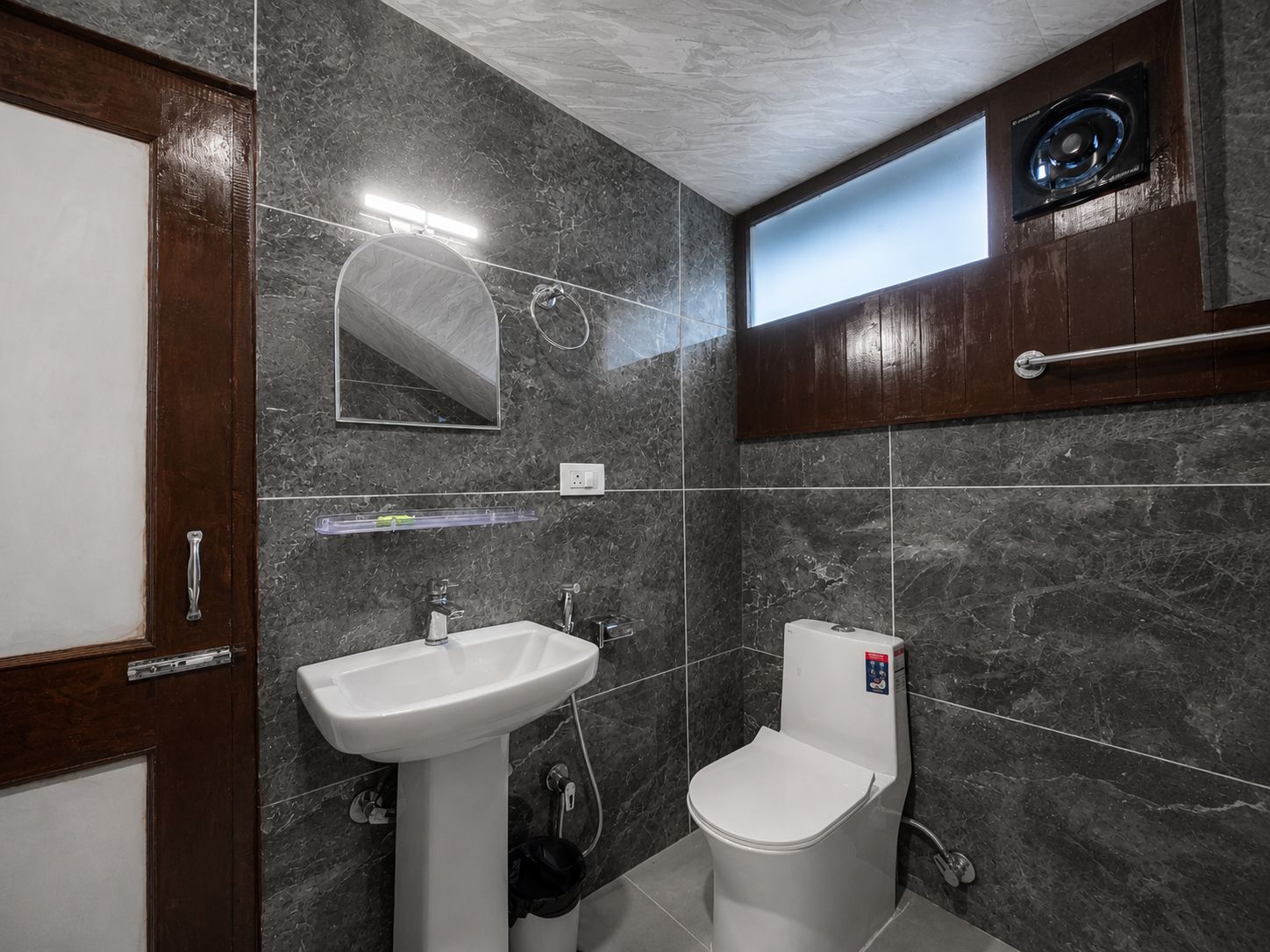A bathroom with a white sink, a toilet, a mirror, and a window.