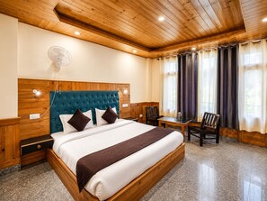 A hotel room with a large bed, wooden headboard, a desk, and a chair.