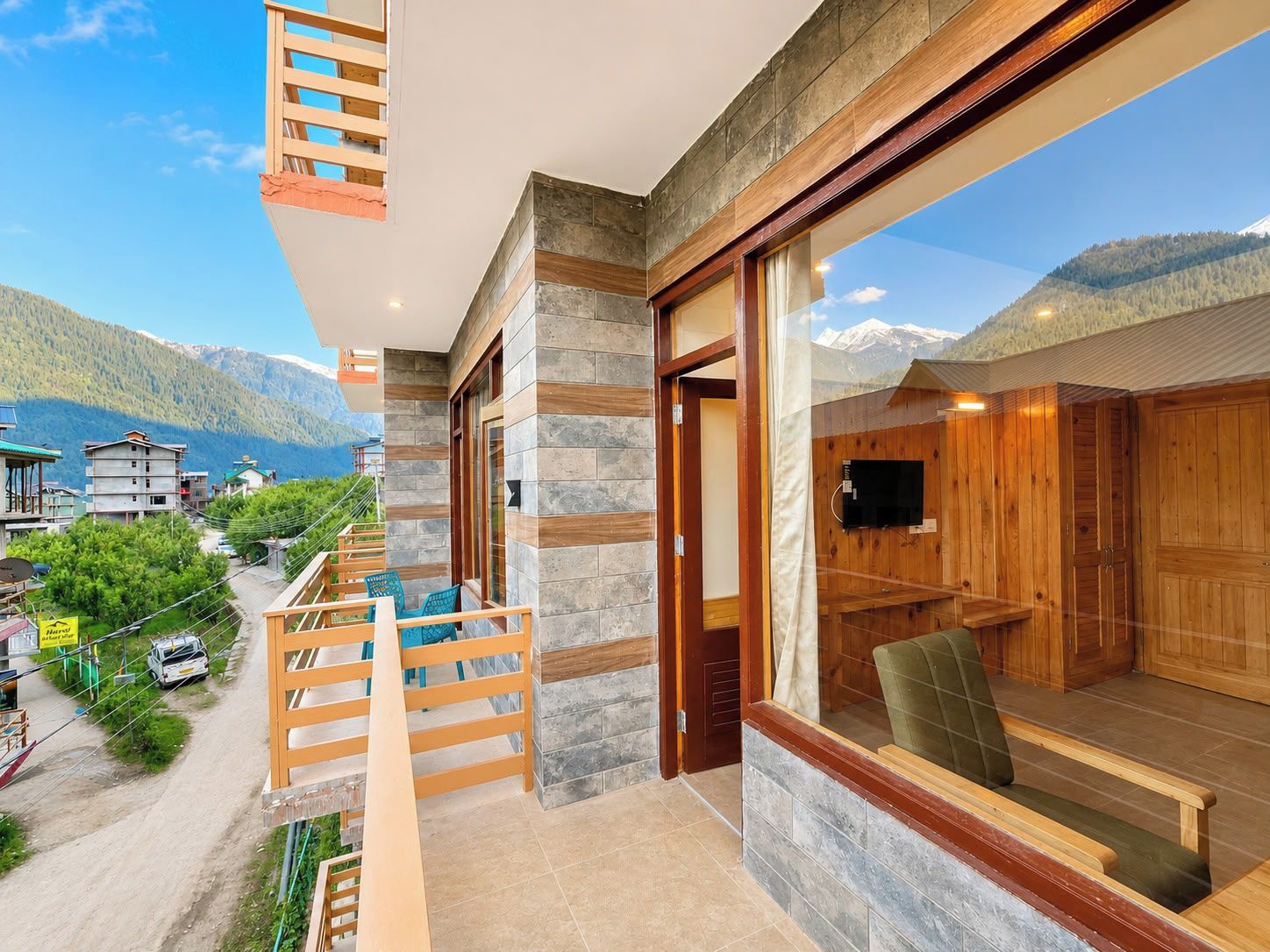 A modern hotel room with a balcony overlooking a mountainous landscape.