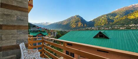 A balcony with a view of a mountain range and a green-roofed building.
