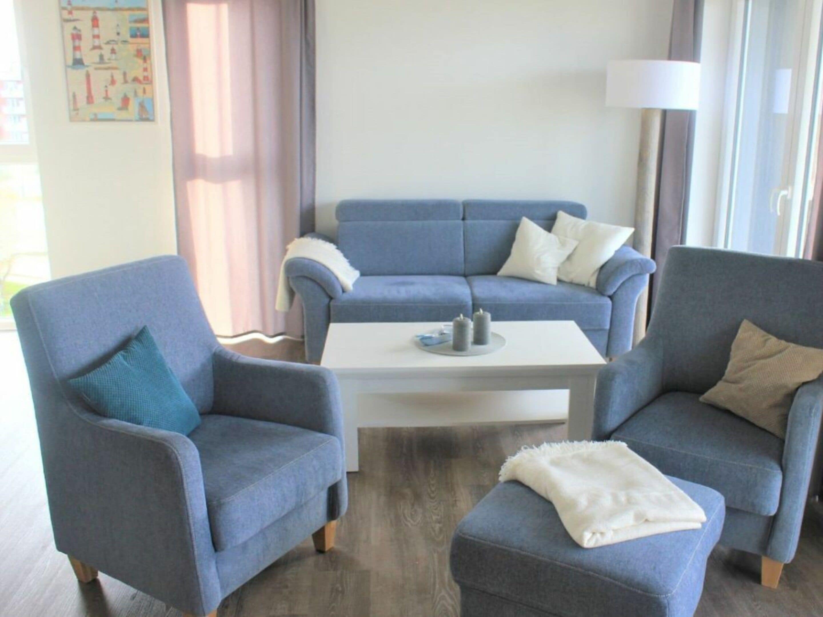 A living room with a blue sofa set, two armchairs, a white coffee table, and a lamp.