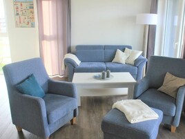 A living room with a blue sofa set, two armchairs, a white coffee table, and a lamp.
