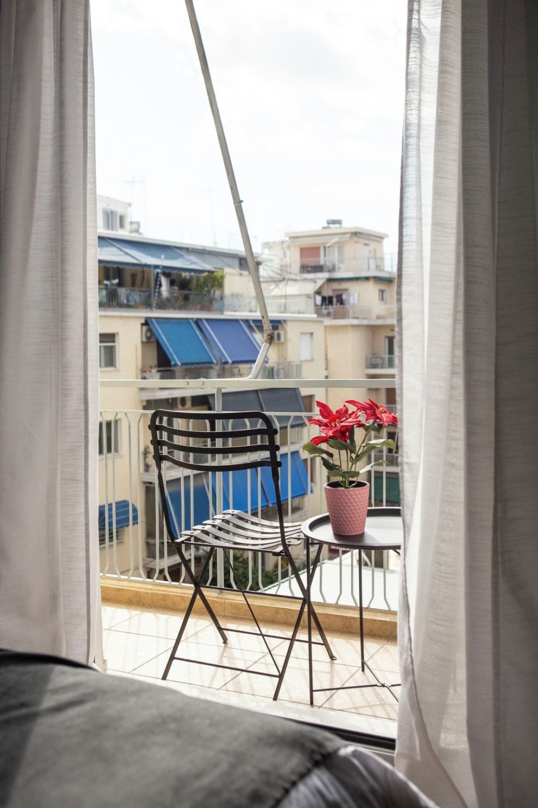 Ein Balkon mit Stuhl, Tisch und einem Blumentopf.