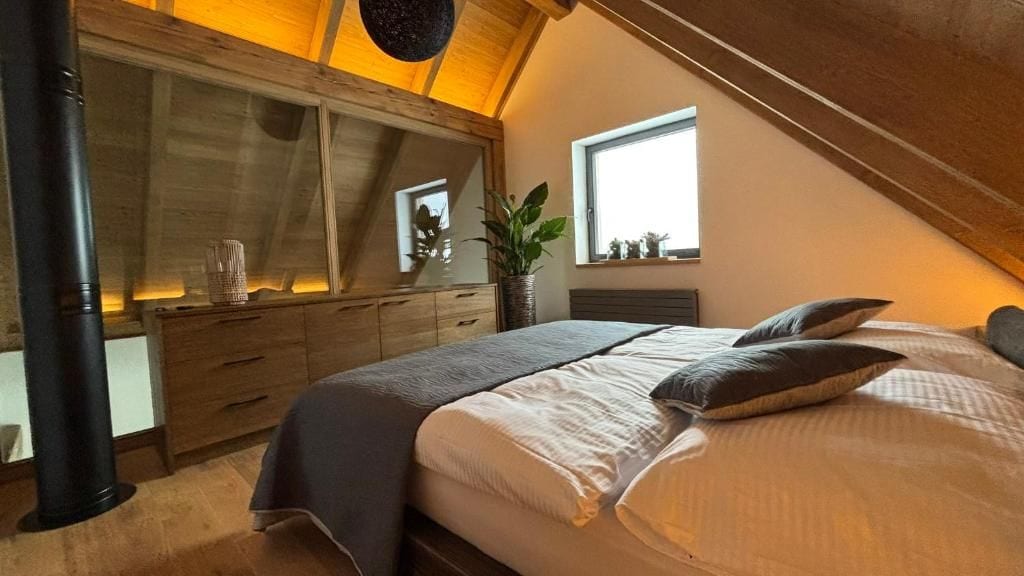 A bedroom with a bed, a dresser, a window, and a plant.