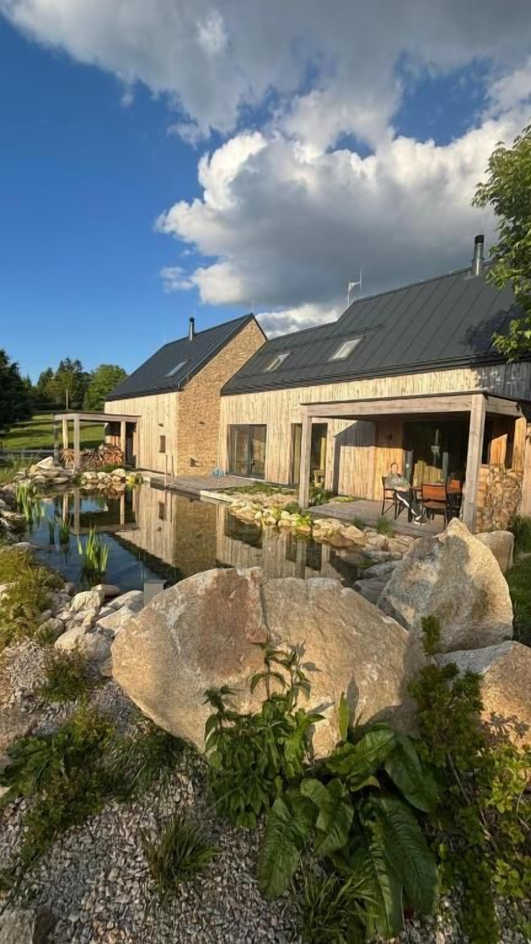 Une maison moderne dotée d’une piscine, entourée de grands rochers et de verdure.