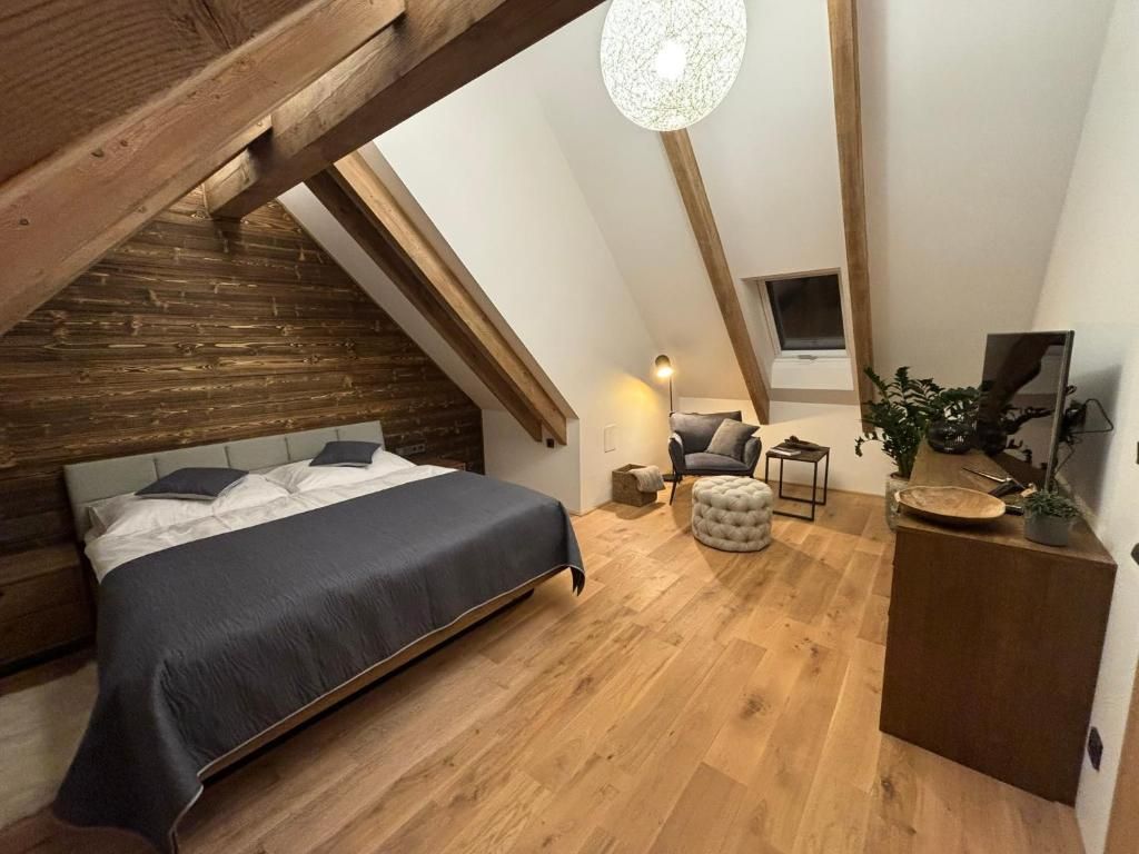 A bedroom with a bed, a chair, a small table, and a desk with a plant.