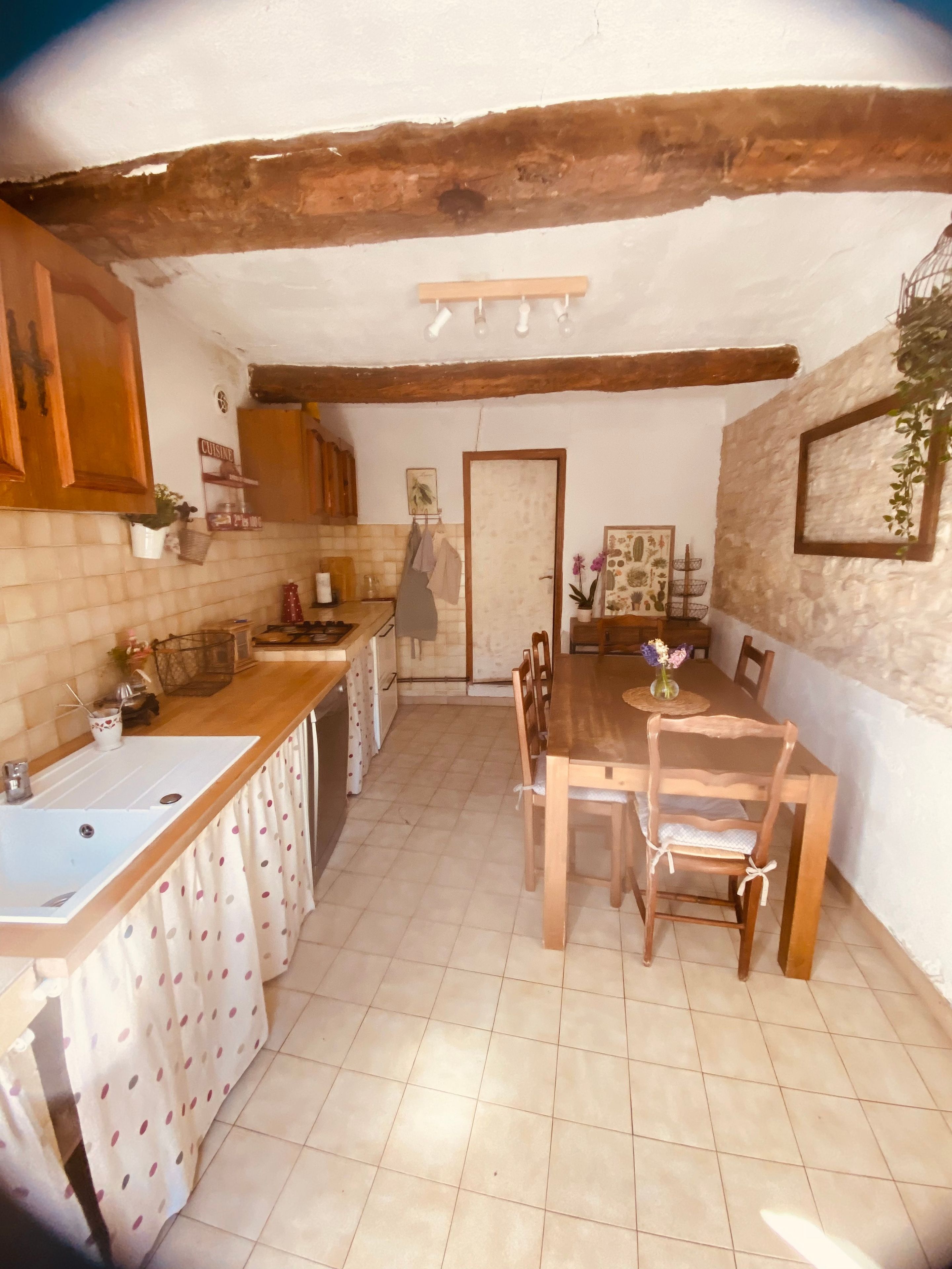A kitchen with a wooden table and chairs, a sink, and a tiled floor.