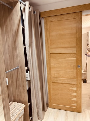 A wooden sliding door with a white towel rack and a basket on the left. - House 'La Petite Maison de Village' with Private Terrace and Wi-Fi in the Heart of Provence (Vachères)