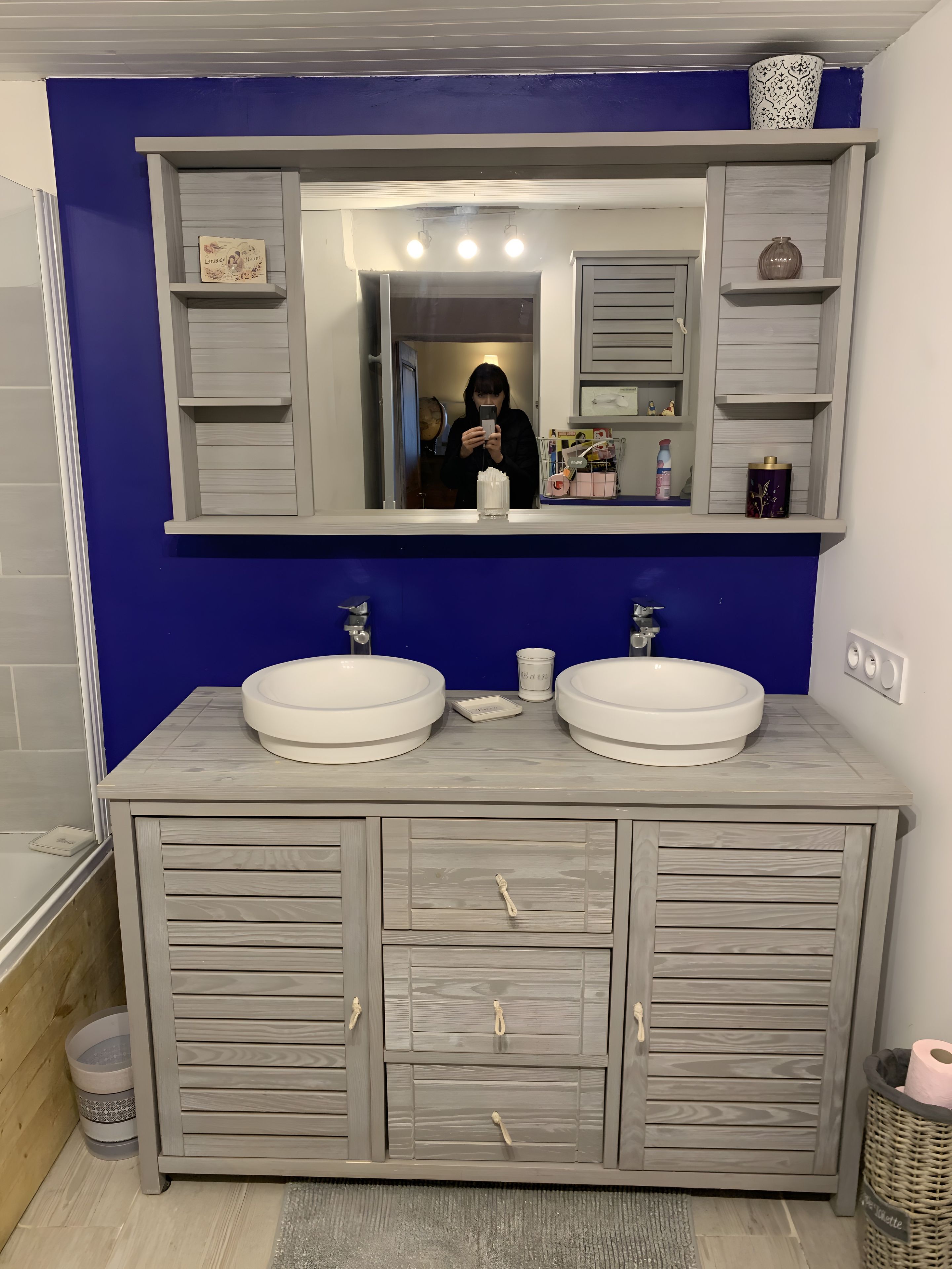 Ein Badezimmer mit zwei Waschbecken, einem Spiegel und einem Waschtisch mit Schubladen.