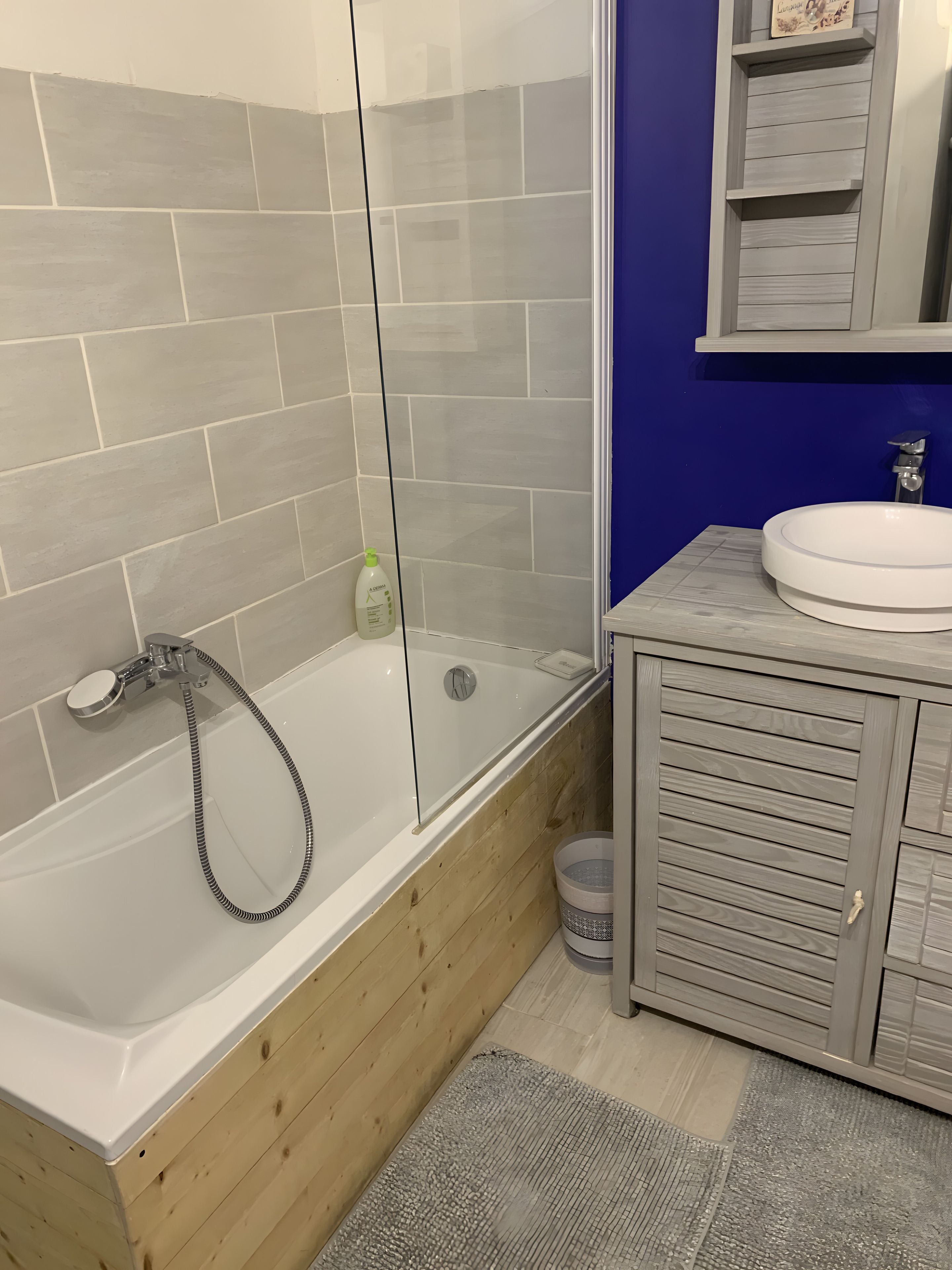 Une salle de bain avec une baignoire, une douche, un lavabo et un meuble-lavabo en bois.