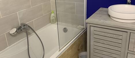 A bathroom with a bathtub, a shower, a sink, and a wooden vanity.