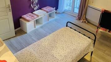 A bedroom with a bed, a dreamcatcher, a window with curtains, and a radiator.