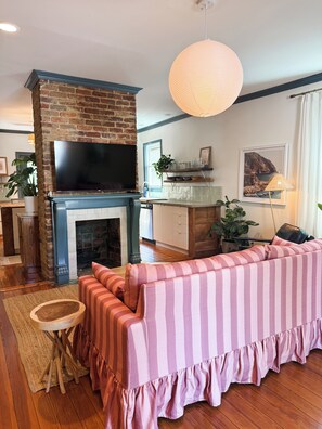 Un salon avec une cheminée, un téléviseur, un canapé et un luminaire suspendu.