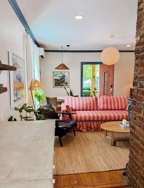 Un salon chaleureux avec un canapé à rayures, une table basse en bois et une grande fenêtre donnant sur un paysage verdoyant.